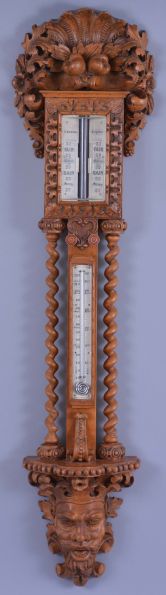 T. Boxell, Brighton, an ornately carved softwood barometer, the base with "green man" mask, trimmed with foliate ornament, beneath a shelf with barley twist columns flanking a thermometer with engraved reamur and fahrenheit scales, the top with engraved barometer scales surrounded by carved trim, and surmounted with a large, removable top carved with scallop shell, fruit and leaves