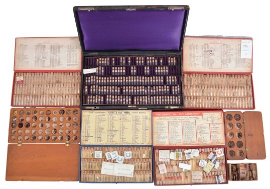 Wrist and pocket watch parts, three large boxes filled with material assortments from various manufacturers, including jewels, staffs, stems, crowns, gaskets, and more, for both Swiss and American watches, together with a box and a metal cabinet each containing hundreds of pocket watch crystals, and a wood pocket watch display case with glass door.