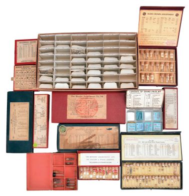 Wrist and pocket watch parts, three large boxes filled with material assortments from various manufacturers, including jewels, staffs, stems, crowns, gaskets, and more, for both Swiss and American watches, together with a box and a metal cabinet each containing hundreds of pocket watch crystals, and a wood pocket watch display case with glass door.