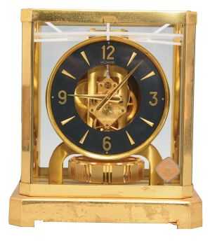 Jaeger- LeCoultre, Switzerland, "Atmos" clock, 15 jewel movement, gilt torsion pendulum, round black painted dial with applied gilt Arabic numerals and arrow markers, gilt hands all contained in a glazed rectangular case with removable front panel, serial #355823.