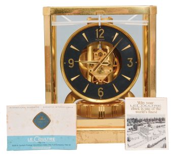 Jaeger- LeCoultre, Switzerland, "Atmos" clock, 15 jewel movement, gilt torsion pendulum, round black painted dial with applied gilt Arabic numerals and arrow markers, gilt hands all contained in a glazed rectangular case with removable front panel, serial #355823.