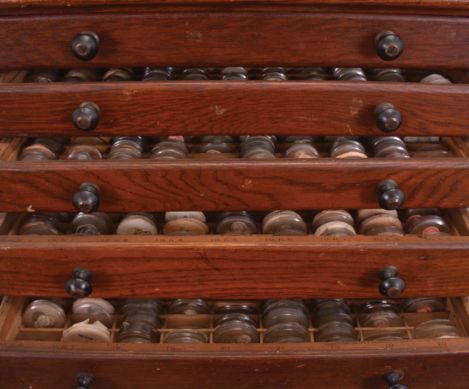 2 (Two) Cabinets of Watch Crystals: one four drawer wood cabinet and one five drawer wood cabinet, both with many pocket and wrist watch crystals. Lot also includes a partial box of crystals.