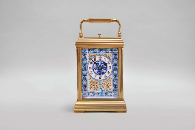 France, attributed to Gaye, Lamaille, & Co., a fine, Aesthetic Movement, porcelain paneled hour repeating carriage clock, the gilt, Cannelee variant case with folding handle, the sides set with panels depicting a potted flower in blue, on a cream ground, also with floral ornament, and with blue, wheatear border, the Arabic numeral dial with ornament matching the side panels, blued steel spade and whip hands, two train, 8 day movement with lever platform, striking the hour and half hour in passing, and repeating the last hour on demand, the back plate marked "Patent Surety Roller", and 1813