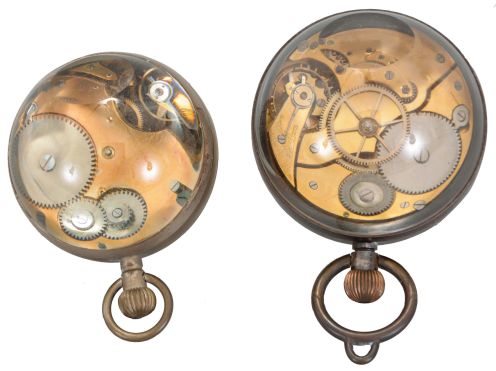 Paperweight clocks- 2 (Two), one marked "Octavia Watch Co.", both with spherical, colorless glass cases and Swiss eight day lever movements, one with Arabic numeral, double sunk white enamel dial, the other with Arabic numeral metal dial, 69mm, 77mm, c1910