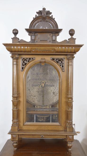 Polyphon Musicwerk, Leipzig, Germany, "Model 104" floor-standing, coin-operated disc music box, playing 19-5/8 inch discs, robust dual comb movement starting upon insertion of a U. S. quarter or Deutschmark piece, the case of mixed walnut and mahogany veneers and solids, all resting on a base cabinet with hinged, locking door. Approximately 2 dozen discs are included.