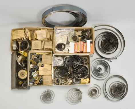 Parts- 6 (Six) boxes of clock parts including many mainsprings, dozens of keys, verges, cables & cord, fasteners, clock oil, wall hooks, gongs, many antique cast metal case parts, and more, together with a group of American and Swiss watch movements, crowns, and wrist watches.