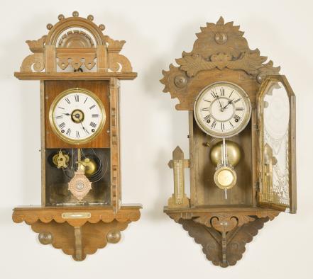 Clocks- 2 (Two): (1) Seth Thomas Clock Co., Thomaston, Conn., "Hanging Eclipse", 8 day, time, strike and alarm spring driven brass movement hanging gingerbread wall clock, c1894 (2) Waterbury Clock Co., Waterbury, Conn., 8 day, time and strike spring driven brass movement unidentified model hanging gingerbread wall clock, c1901