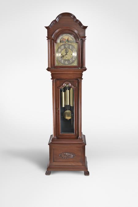 Tiffany & Co., New York, NY, hall clock, 8 day, time, strike and chime on five tubular bells, three brass weight driven movement in a mahogany case with arched top, full turned columns flanking hood door and oval side lights over a trunk door with beveled glass and fancy molded top flanked by full turned columns resting on a base with recessed panel and applied carving with paw feet. The brass dial has Tiffany signature, silvered chapter ring, subsidiary seconds, chime / silent disc, engraved dial center and spandrels and moon phase.