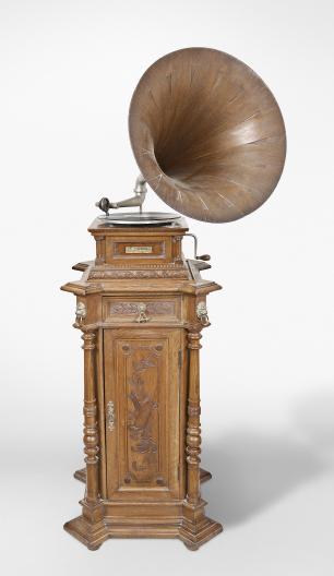 The Gramophone & Typewriter Ltd., 21 City Rd, Finsbury Square, London, England, the English subsidiary of Victor Talking Machine Co., "Type D" oak cased phonograph with original 21" diameter oak horn, 21" resting on an oak and quarter sawn oak record cabinet with single drawer over a single cabinet flanked by full turned columns flanking panels with carved musical trophies. Includes three albums of records.