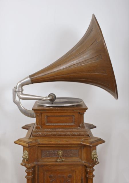 The Gramophone & Typewriter Ltd., 21 City Rd, Finsbury Square, London, England, the English subsidiary of Victor Talking Machine Co., "Type D" oak cased phonograph with original 21" diameter oak horn, 21" resting on an oak and quarter sawn oak record cabinet with single drawer over a single cabinet flanked by full turned columns flanking panels with carved musical trophies. Includes three albums of records.