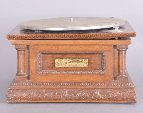 The Gramophone & Typewriter Ltd., 21 City Rd, Finsbury Square, London, England, the English subsidiary of Victor Talking Machine Co., "Type D" oak cased phonograph with original 21" diameter oak horn, 21" resting on an oak and quarter sawn oak record cabinet with single drawer over a single cabinet flanked by full turned columns flanking panels with carved musical trophies. Includes three albums of records.