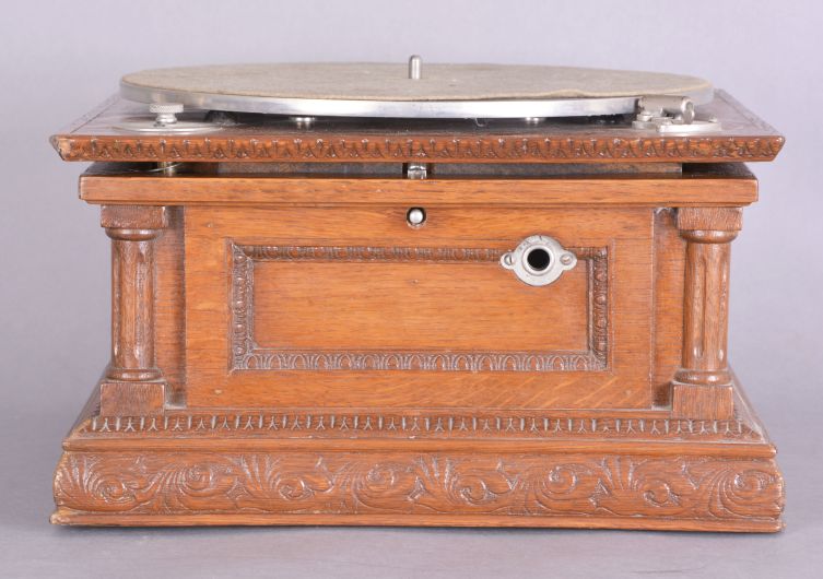 The Gramophone & Typewriter Ltd., 21 City Rd, Finsbury Square, London, England, the English subsidiary of Victor Talking Machine Co., "Type D" oak cased phonograph with original 21" diameter oak horn, 21" resting on an oak and quarter sawn oak record cabinet with single drawer over a single cabinet flanked by full turned columns flanking panels with carved musical trophies. Includes three albums of records.