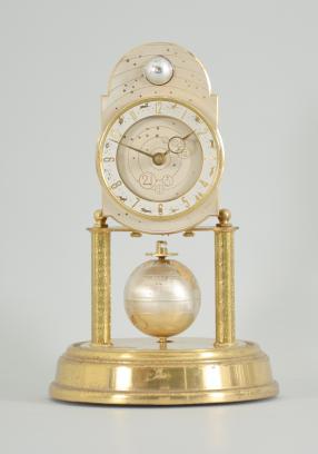 J. Kaiser GmbH, Villingen, Germany, "Universe" 400-day clock, year running, spring driven brass movement with metallic rotating globe torsion pendulum and moon phase dial, monochrome zodiac dial, white chapter with polished brass numerals, brass hands, all under a glass dome.