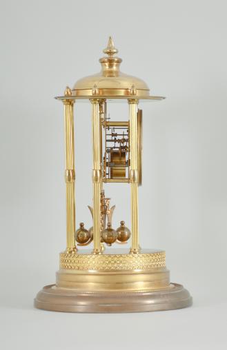 Kienzle GmbH, Schwenningen, Germany, Louvre style 400-day clock, year running, time only, spring driven torsion pendulum movement in a polished brass case with six fluted columns, arabic numeral arcaded enamel dial, all under a glass dome.