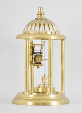 Kienzle GmbH, Schwenningen, Germany, Louvre style 400-day clock, year running, time only, spring driven movement with torsion pendulum and gimbaled suspension mount in a polished brass case with five columns, arabic numeral white enamel dial, all under a glass dome fitted inside of the columns and capped with a pierced dome.