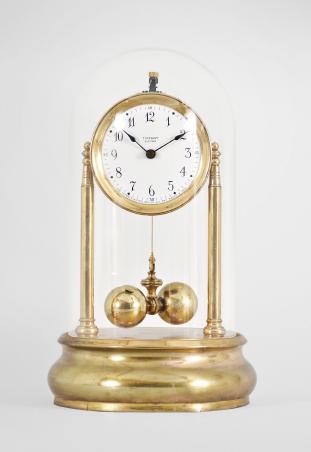 Tiffany Electric Mfg. Co., New York, NY, "Tiffany Electric" larger battery-powered clock with torsion pendulum on a polished brass base, arabic numeral white enamel dial, black steel spade style hands, all under a glass dome.