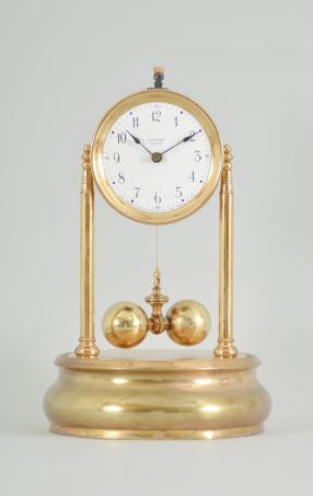 Tiffany Electric Mfg. Co., New York, NY, "Tiffany Electric" larger battery-powered clock with torsion pendulum on a polished brass base, arabic numeral white enamel dial, black steel spade style hands, all under a glass dome.