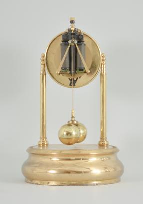 Tiffany Electric Mfg. Co., New York, NY, "Tiffany Electric" larger battery-powered clock with torsion pendulum on a polished brass base, arabic numeral white enamel dial, black steel spade style hands, all under a glass dome.