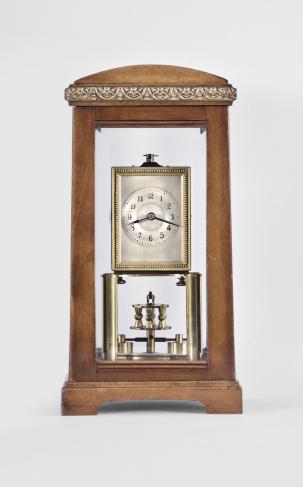 Gustav Becker, Freiburg, Germany for B.H. Abrahams, London, 400-day clock, year running, time only, spring driven brass movement with torsion pendulum in a glazed hardwood case with arch top, arabic numeral silvered dial, and black steel spade hands.

