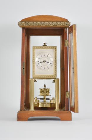 Gustav Becker, Freiburg, Germany for B.H. Abrahams, London, 400-day clock, year running, time only, spring driven brass movement with torsion pendulum in a glazed hardwood case with arch top, arabic numeral silvered dial, and black steel spade hands.

