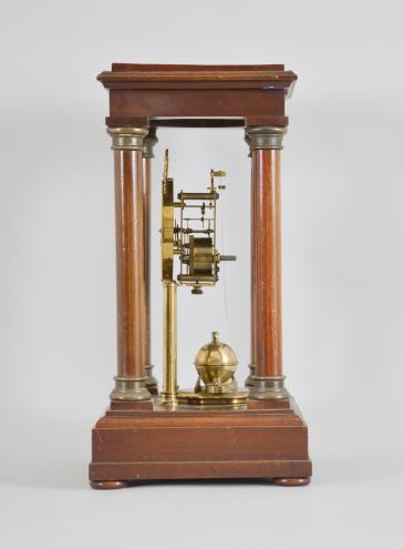 Gustav Becker, Freiburg, Germany, 400-day clock, year running, time only, spring driven movement in a four-column Empire style mahogany case with hinged top and central glass cylinder, arabic numeral white enamel dial, blued steel poker hands, and disc pendulum topped with brass sphere. 
