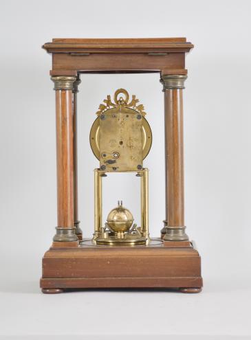 Gustav Becker, Freiburg, Germany, 400-day clock, year running, time only, spring driven movement in a four-column Empire style mahogany case with hinged top and central glass cylinder, arabic numeral white enamel dial, blued steel poker hands, and disc pendulum topped with brass sphere. 
