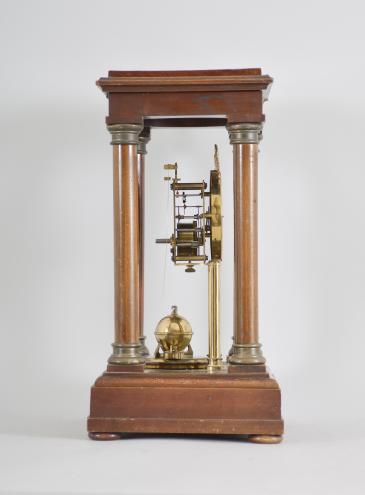 Gustav Becker, Freiburg, Germany, 400-day clock, year running, time only, spring driven movement in a four-column Empire style mahogany case with hinged top and central glass cylinder, arabic numeral white enamel dial, blued steel poker hands, and disc pendulum topped with brass sphere. 
