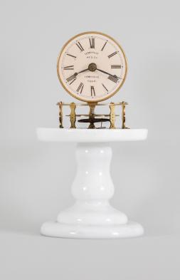 Terryville Manufacturing Company, Terryville, Conn., candle stand clock, 30 hour, time only, spring driven brass movement with four-arm balance wheel movement, 2.75 inch paper on zinc dial signed "Terryville Mfg. Co. / Terryville / Conn.", black steel hands, all on a white milk glass pedestal under small glass dome.