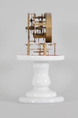 Terryville Manufacturing Company, Terryville, Conn., candle stand clock, 30 hour, time only, spring driven brass movement with four-arm balance wheel movement, 2.75 inch paper on zinc dial signed "Terryville Mfg. Co. / Terryville / Conn.", black steel hands, all on a white milk glass pedestal under small glass dome.