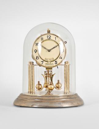 W. Petersen Uhrenfabrik, Schwenningen, Germany, 400-day clock, year running, time and calendar showing day of the week, day of the month, and month, spring driven two-train movement with torsion pendulum on a brass base, arabic numeral painted metal dial, black steel hands.