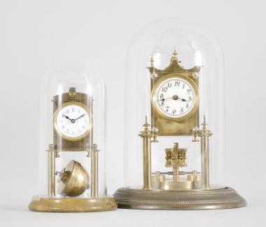 Clocks- 2 (Two) miniature 400-day (1) Phillip Hauck, Munich, Germany, "Semester Uhr" or half-year clock, 200-day, time only, spring driven movement with torsion disc pendulum on a brass base, arabic numeral white enamel dial, under small glass dome, c1906; (2) Kienzle GmbH, Schwenningen, Germany, miniature torsion pendulum clock, 30 day, time only, spring driven movement pin-pallet escapement and semi-spherical torsion pendulum on a polished stone base and under a glass dome, c1910.