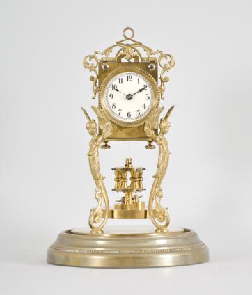 Attributed to Andreas Huber, Munich Germany or Jahresuhrenfabrik, Triberg, Germany, 400 day clock, year running, time only, spring driven movement with torsion pendulum on a brass base with gilt cast caryatid figures supporting the movement, arabic numeral cream enamel dial with black spade hands, all under a glass dome.