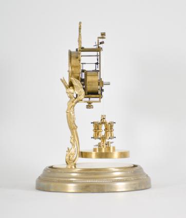 Attributed to Andreas Huber, Munich Germany or Jahresuhrenfabrik, Triberg, Germany, 400 day clock, year running, time only, spring driven movement with torsion pendulum on a brass base with gilt cast caryatid figures supporting the movement, arabic numeral cream enamel dial with black spade hands, all under a glass dome.