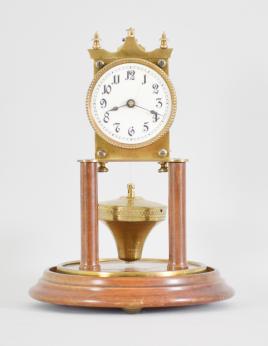 Kienzle GmbH, Schwenningen, Germany, 400-day clock, year running, time only, spring driven brass movement with torsion pendulum and rare Phillip Hauck style pendulum, wood pillars and base, roman numeral white enamel dial with black steel spade hands, all under a glass dome.