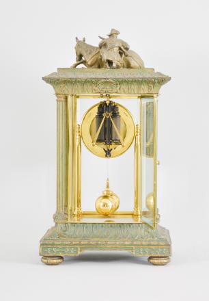 Tiffany Electric Mfg. Co., New York, NY, "Tiffany Electric" large mantel clock, battery-powered movement with torsion pendulum in a glazed crystal regulator style case with leaf-and-dart molded base and top, four fluted columns at the corners, surmounted by the cast figure of a cowboy crouched behind his horse with his rifle, arabic numeral white enamel dial, black steel spade hands, and two-ball polished brass pendulum.