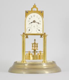 Kienzle GmbH, Schwenningen, Germany, 400-day clock for the French market, year running, time and calendar, spring driven brass movement with torsion pendulum, arched enamel dial with arabic numerals and subsidiary dials for day of the month and day of the week, black steel spade hands, all under a glass dome.