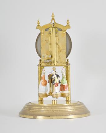 Forestville Clock Co., Germany, 400-day clock, year running, spring driven brass movement with torsion pendulum, brass base and posts holding movement, arabic numeral arcaded white enamel dial, black steel spade hands, and pendulum with ceramic dancing figures, all under a glass dome. 










