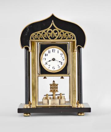 Jahresuhrenfabrik, Triberg, Germany, 400-day clock, year running, time only, spring driven movement with torsion pendulum disc on a polished stone base with four columns supporting a curved brass roof, the central portion containing the clock is glazed on four sides, arabic numeral white enamel dial, black steel spade hands.