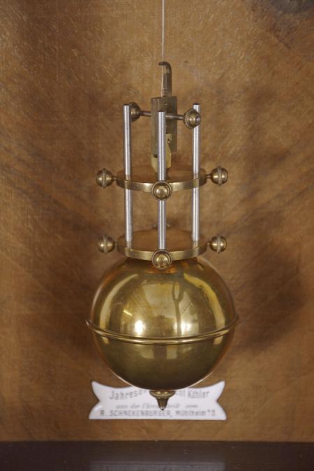 R. Schnekenburger, Germany, to the design of Wilhelm Kohler, a rare hanging, striking 400 day clock with torsion pendulum and pivoted detent escapement, the walnut veneered Alt Deutsch style case with incurved bottom bracket and turned drops, the glazed door with reeded columns having vasiform tops and bases, and top with projecting cornice molding, two piece, roman numeral white enamel dial, and fancy pierced steel hands, two train brass movement with pivoted detent escapement and count wheel striking, and heavy spherical pendulum, the backboard with white enamel, beat scale shaped plaque marked "Jahresuhr Patent Kohler aus der Uhrenfabrik von R. Schneckenburger Muhlheim a/D", serial #1084