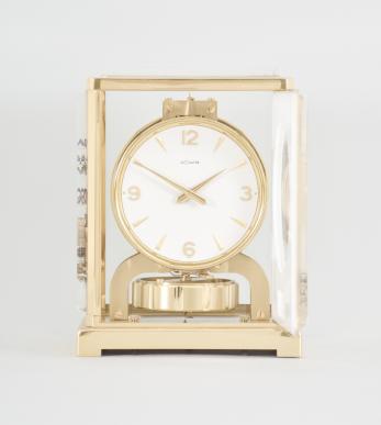 Jaeger-LeCoultre, Switzerland, Atmos "Marina" model, 526-5 caliber jeweled movement with torsion pendulum, in a gilt case with frosted acrylic panels having gold Asian motifs, signed round white dial, gilt arabic numerals, and gold hands over a rectangular pendulum aperture.