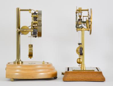 Clocks- 2 (Two) Electromechanical shelf clocks (1) England, mantel clock, battery powered movement electromagnet pendulum encircling a segment of permanent magnet, skeletonized brass movement on two posts mounted to a molded wood base, arabic numeral silvered dial, black steel hands, all under an clear acrylic box with arched top, c1935; (2) Barr Mfg. Corp., Weedsport, NY, mantel clock, electric battery movement in a brass frame, silvered dial with subsidiary seconds, black steel hands, all under a glass dome resting on a turned wood base, c1938.