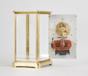 Clocks- 2 (Two), both electromechanical, the first signed "Electric- Silentia Besancon", polished brass crystal regulator style case with mirrored back, roman numeral white enamel dial with black steel hands, round, jeweled watch movement with large balance with horseshoe magnet and rotor below, rewinding the small mainspring barrel every 45 minutes, serial #64, the other by the "Prentiss Clock Improvement Co.", arabic numeral white enamel dial and round brass pin lever movement mounted to a strip brass frame, flanked by two electromagnetic coils, periodically energized and resetting a pivoted horizontal bar with coil spring, it