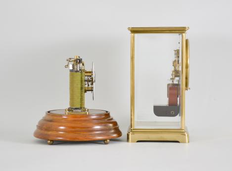 Clocks- 2 (Two), both electromechanical, the first signed "Electric- Silentia Besancon", polished brass crystal regulator style case with mirrored back, roman numeral white enamel dial with black steel hands, round, jeweled watch movement with large balance with horseshoe magnet and rotor below, rewinding the small mainspring barrel every 45 minutes, serial #64, the other by the "Prentiss Clock Improvement Co.", arabic numeral white enamel dial and round brass pin lever movement mounted to a strip brass frame, flanked by two electromagnetic coils, periodically energized and resetting a pivoted horizontal bar with coil spring, it