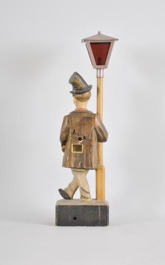 Karl Griesbaum, Triberg, Germany, carved "Hobo" or "Drunkard" whistling figure, spring driven brass movement driving a bellows, cam-controlled slide whistle, and head turn motion enclosed in a hand carved wood figure depicting an inebriated man in a top hat who leans on a lamp post, the top of which contains a battery powered bulb behind red glass.