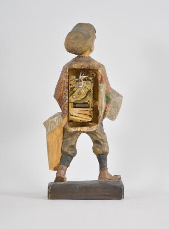 Karl Griesbaum, Triberg, Germany, "Newsboy" whistling figure, spring driven brass movement driving a bellows, cam-controlled slide whistle, and head motion, enclosed in a hand carved wood figure depicting a boy in a flat cap and nickers with a newspaper under one arm and a bag full of papers hanging at his side.