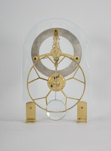 Reproduction skeleton clock, 8 day, time only, spring driven movement with silk thread suspension mounted on two sides of an arched glass plate with etched floral border, brass feet, roman numeral silvered chapter ring with blued steel hands.