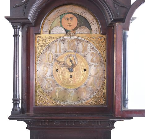 Germany, tall clock, 8 day, time, strike and chime on gongs, three brass weight driven movement in a mahogany case with beveled glass trunk door, broken arch top, paw feet, three wooden finials and applied moldings on base with brass dial, silvered chapter ring, applied brass spandrels, moon phase and seconds bit.