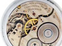 Hamilton Watch Co., Lancaster, Penn., "992E" with unusual regulation and balance spring, 16 size, 21 jewels, stem wind and lever set, adjusted, damascened nickel plate movement with lever escapement, uncut, monometallic balance with gold timing screws, and balance spring with straight overcoil, studded at the back of the balance cock, and with linear regulator in a nickel, screw back and bezel open face case, luminous Arabic numeral and arrow marker black metal dial, skeletonized luminous hands, serial #2587492, c1930.