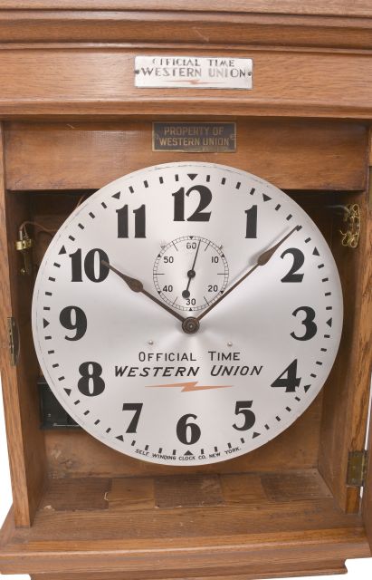 Self Winding Clock Company, New York, "No. 10-A Self Winding Clock", spring driven movement with deadbeat escapement and battery wind mechanism in an oak case with 14 inch aluminum dial reading "Official Time / Western Union ".