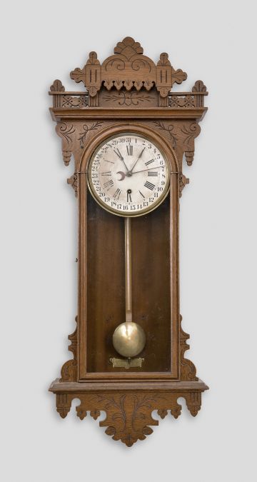 Ansonia Clock Co., New York, for Metropolitan Manufacturing Co., "Eclipse" hanging gingerbread clock, 8 day, time and simple calendar, spring driven movement in an oak case.